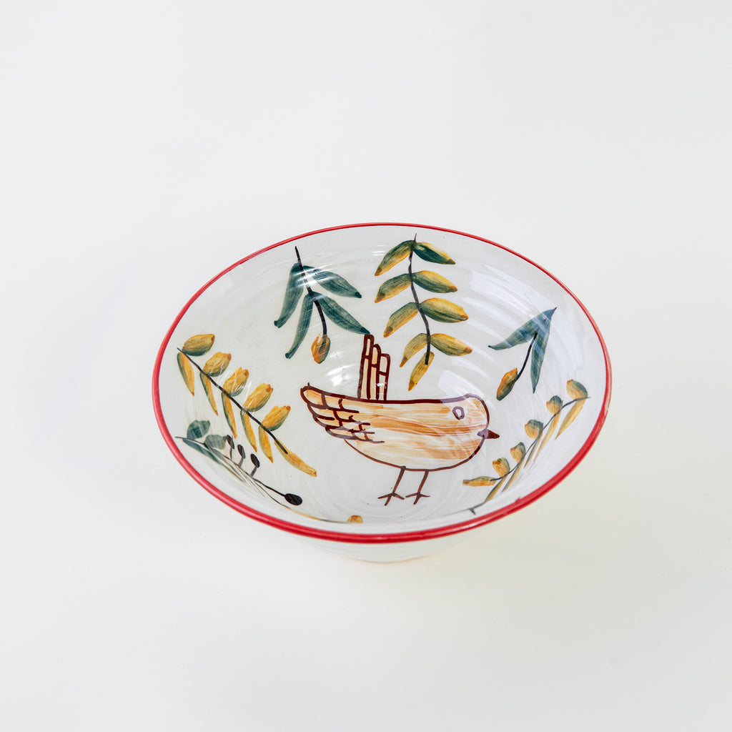 Ceramic serving bowl with a bird print, handcrafted design and red rim on a white background.