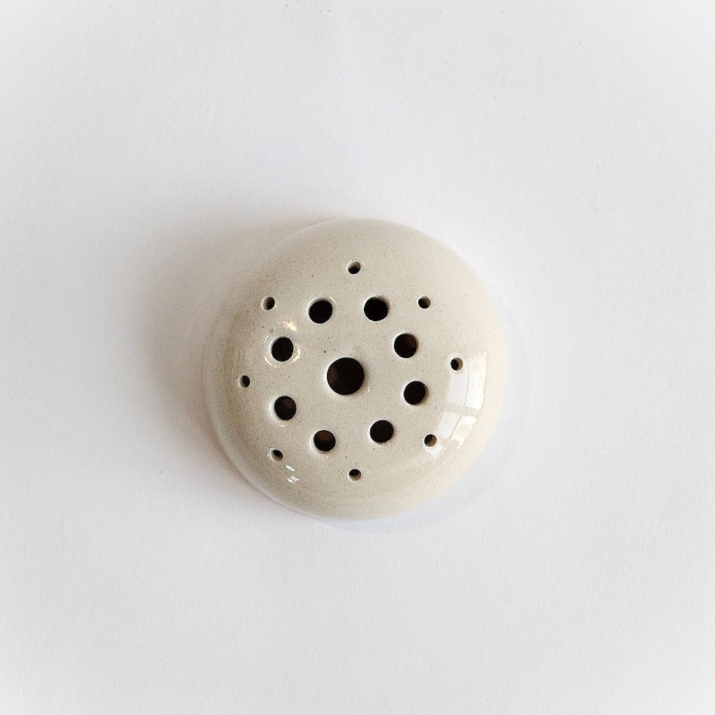 White ceramic flower frog holding stems in an arrangement
