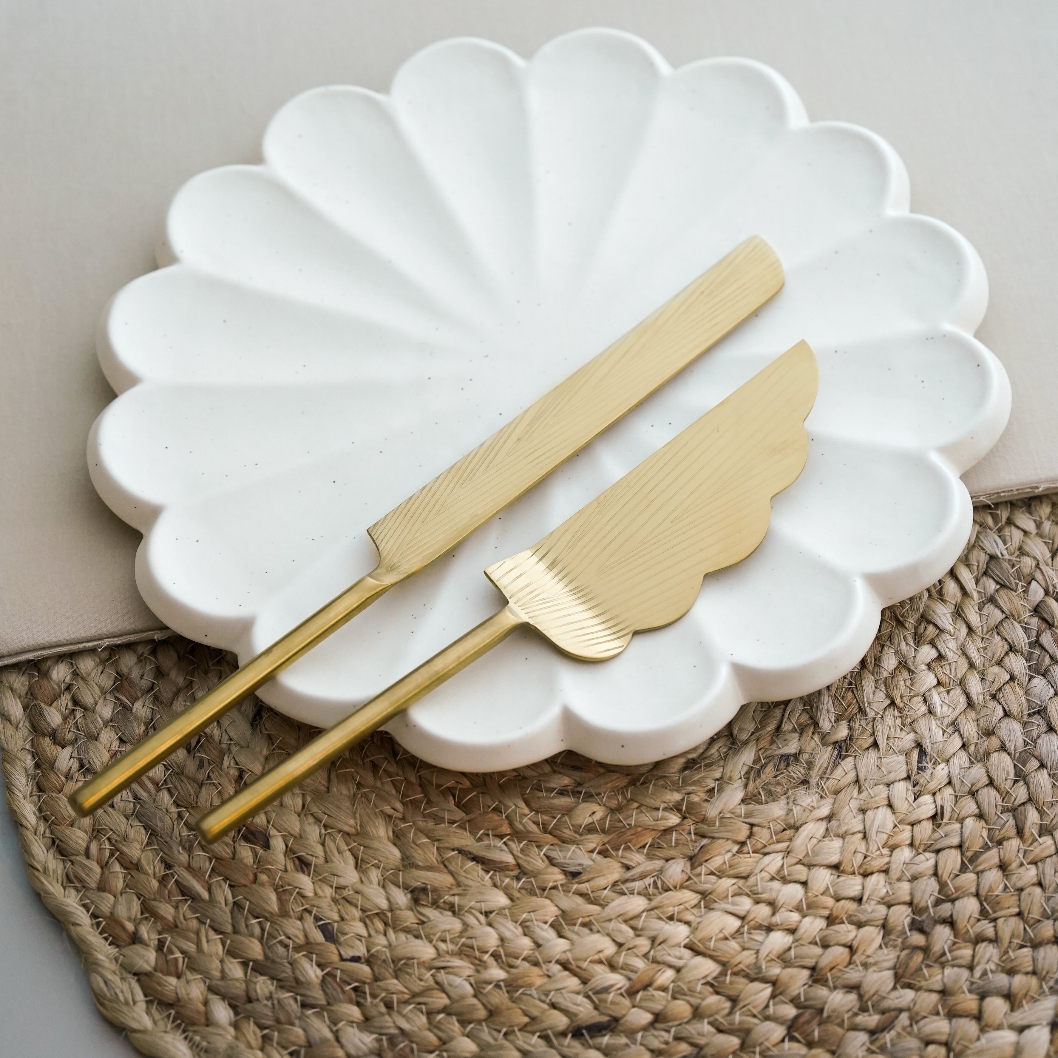 A brass cake knife and server set with a serrated edge and gold finish