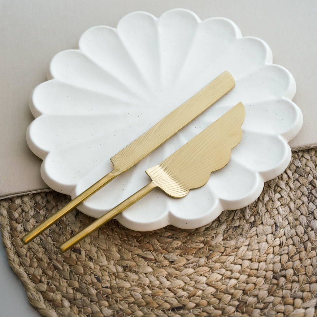 A brass cake knife and server set with a serrated edge and gold finish