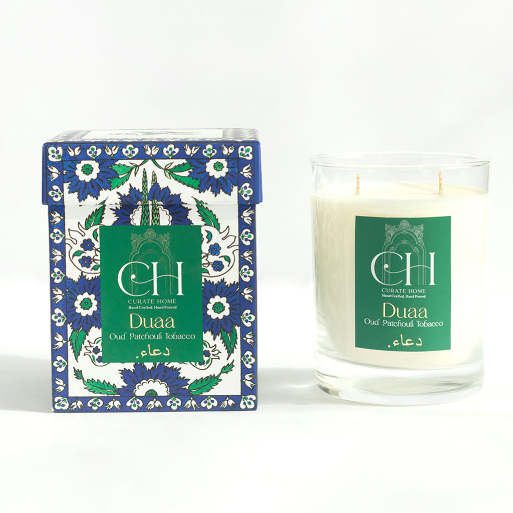 A scented soy candle named 'Duaa' with Oud Patchouli Tobacco fragrance, presented in a decorative box with floral and geometric patterns.