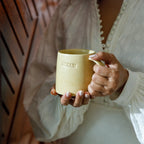 A person holding one of the two beige ceramic mugs with the word 'Helm' engraved on it.