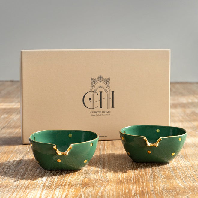 Two pomegranate shaped green ceramic bowls with gold accents in a box as gift