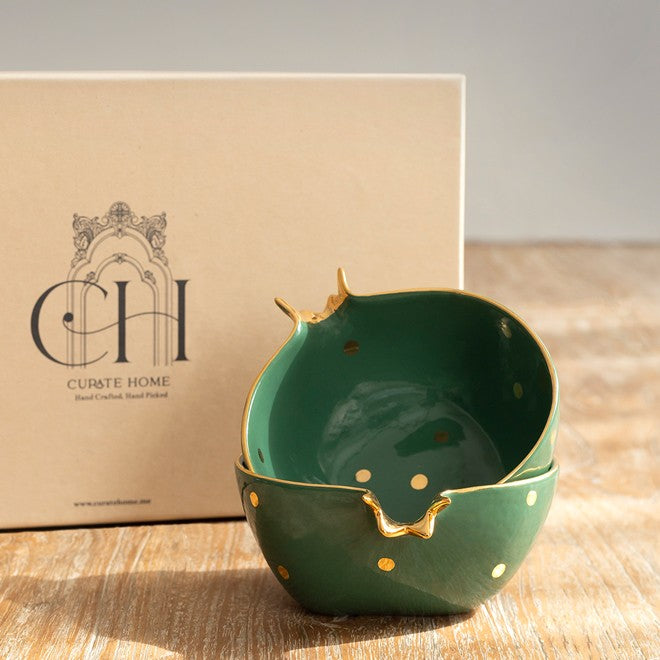 Two pomegranate shaped green ceramic bowls with gold accents in a gift box