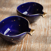 Two blue ceramic bowls with gold accents on a wooden surface