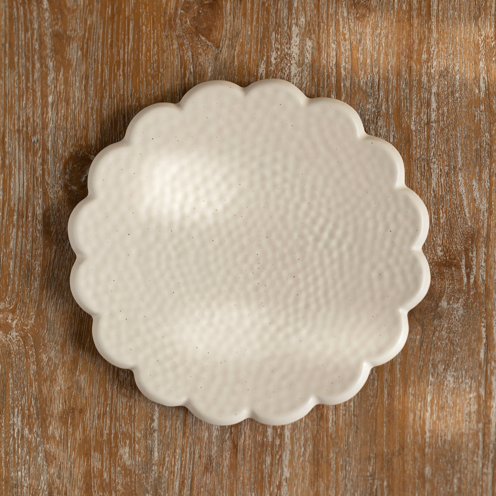 A beige, round, Ceramic stoneware serving platter with a scalloped edge, placed on a wooden surface. Diameter 30.5 cms.