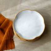 A set of four dinner plates made of a ceramic stoneware with contemporary curved edges, set off food beautifully.